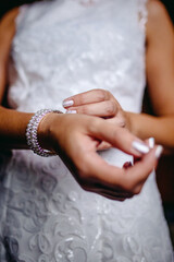 A detailed close-up of a bride adjusting a delicate wrist corsage, capturing the intricate details and the tender moments of the wedding preparation.