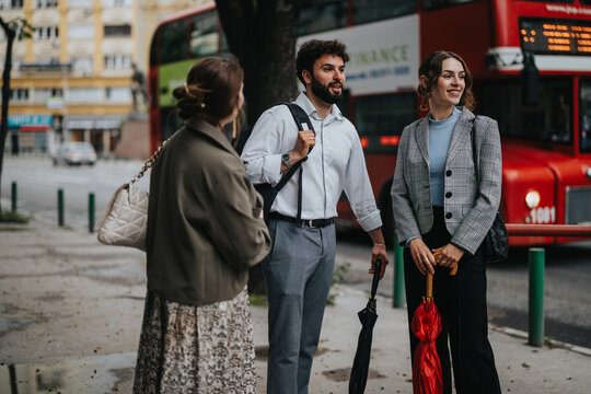 Group of business professionals engaging in a casual conversation outdoors near a red bus. The setting is urban and professional.