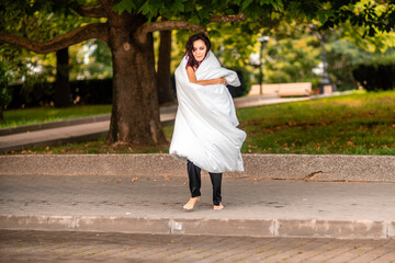 Woman city blanket. Morning in the big city. A blonde woman in a white blanket is enjoying in the city center. Photographed for social media