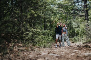 Young couple hikers capturing a selfie moment while exploring a sunny forest trail, surrounded by lush greenery.
