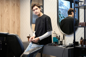Obraz premium Experienced barber posing at camera in contemporary hairdressing salon