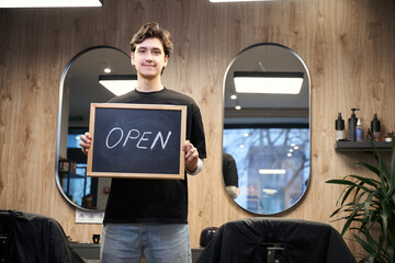 Experienced barber posing at camera in hairdressing salon