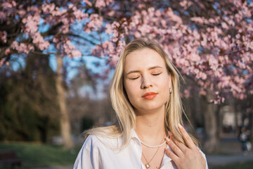 Woman with cherry flowers surrounded by blossoming trees copy space. Beauty and seasonal change and spring bloom season concept.