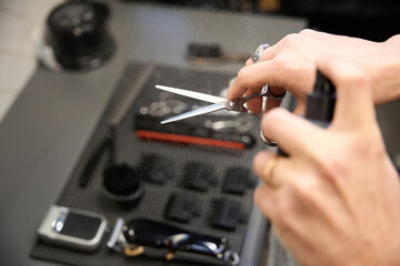 Cropped view of hairdresser cleaning scissors in barbershop