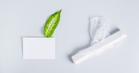 Roll of clean transparent plastic bags, sheet for inscription and fresh leaf on blue background