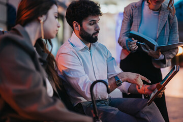 Young business professionals having an outdoor meeting discussing marketing, sales, and revenue growth strategies. They are brainstorming ideas and analyzing reports for their small company expansion.