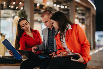 Young corporate business partners engaged in a collaborative discussion, using a laptop and documents in a modern office environment.