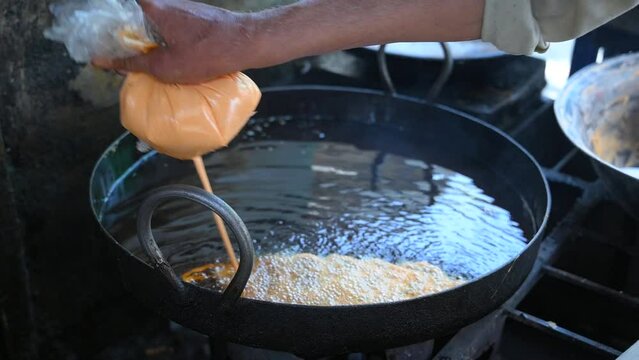 Jalebi is a popular sweet snack in South Asia. Making traditional sweet orange jalebi snacks in Pakistan street food market.