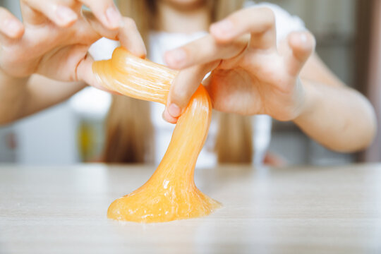Adorable little girl holding a slime toy, a popular homemade toy all over the world. A child plays with slime and stretches it.