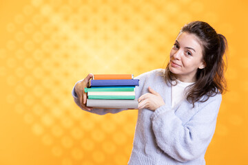 Portrait of upbeat woman holding pile of books, recommending reading, studio background. Radiant...