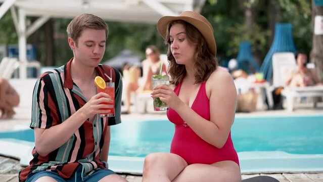 Couple having drinks by the pool, enjoying a sunny day, creating a happy summer holiday atmosphere