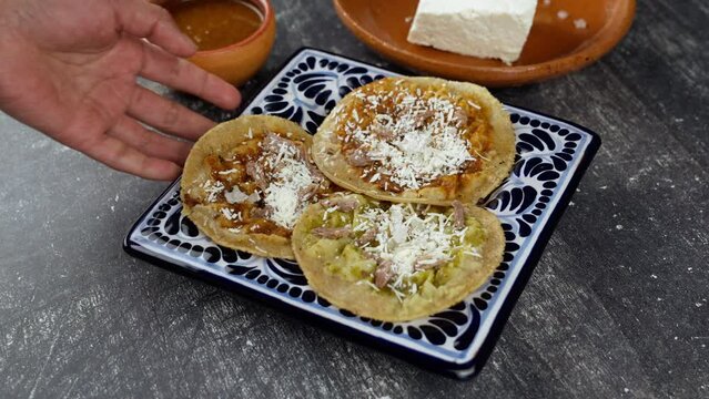 Mexican wife places a plate of talavera with chalupas