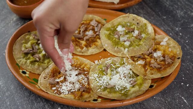 Mexican wife sprinkles cheese on chalupas