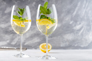 Hugo Spritz Cocktail in Glasses Garnished with Mint and Lemon on Concrete, Copy Space