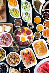 Fresh Traditional Turkish Breakfast on the black surface with copper egg pan and white plates,vertical image
