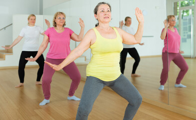 Fototapeta premium Group of mature active women practicing yoga, standing together in asana