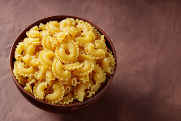Traditional Italian Pasta Creste di Gallo in Shape of Rooster's Comb in Clay Bowl, Copy Space