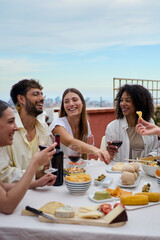 Vertical. Laughing group diverse young friends enjoying lunch together outdoors. Cheerful people...
