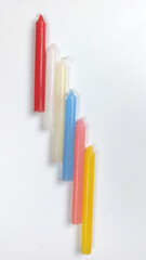 Candles in different colors on a white background.