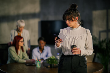 Elegant businesswoman typing on a phone on meeting of interracial team