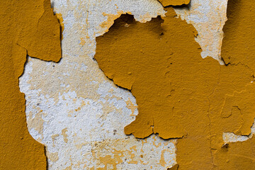 parte di vecchio muro abbandonato, dai colori bianco e giallo, con varie parti della pittura che...