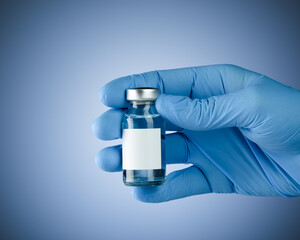 Hand in blue medical gloves holding a vaccine vial with blank white space for text. Healthcare concept with copyspace for text.