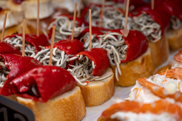 Typical snack of Basque Country, pinchos or pinxtos skewers with small pieces of bread, sea food, eggs, cheese, jamon served in bar in San-Sebastian or Bilbao, Spain, close up