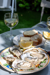 Plate with fresh live oysters with citron, bread, butter and white wine served at restaurant in oyster-farming village, Arcachon bay, Gujan-Mestras port, France