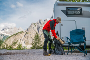Man Packing Backpack Near Motorhome in Mountainous Area