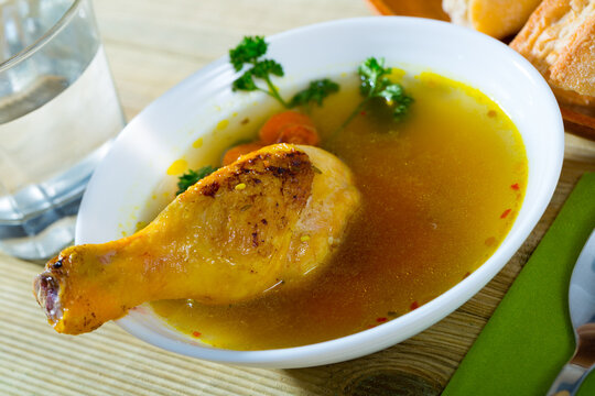 Bowl of homemade chicken bouillon with carrot and herbs and garlic