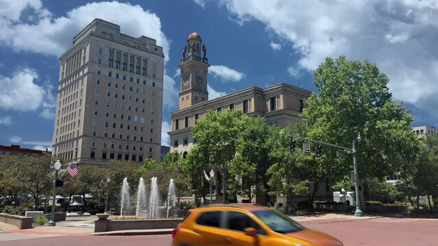 An extreme wide shot view of the Stark County Courthouse along Market Avenue in downtown Canton, Ohio on a sunny summer's day. Traffic passes.  	
