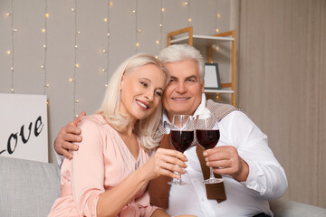 Happy mature couple with glasses of wine at home