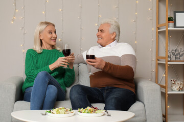 Happy mature couple with glasses of wine at home