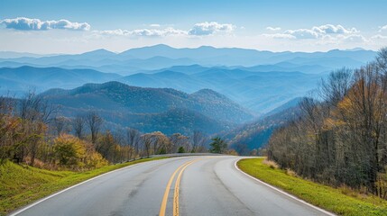 Naklejka premium Mountain road with scenic blue sky and layered hills in the background
