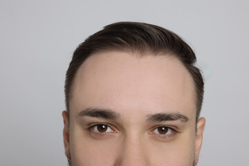 Fototapeta premium Baldness concept. Man with receding hairline on light grey background, closeup
