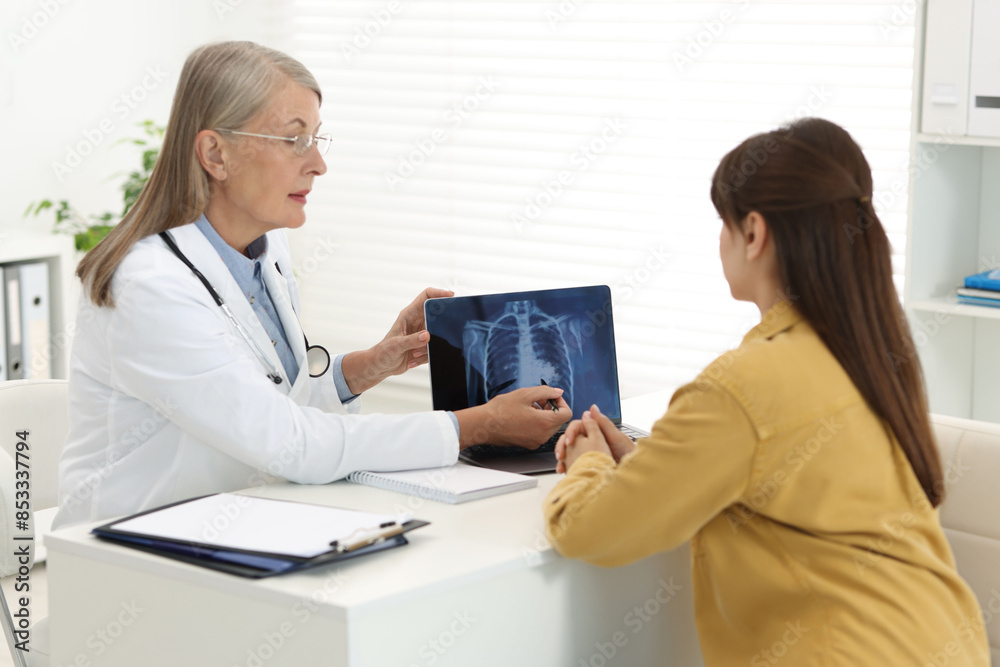 Poster lung cancer. doctor showing chest x-ray on laptop to her patient in clinic