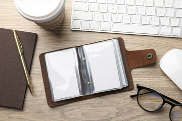 Leather business card holder with blank cards, stationery and keyboard on wooden table, flat lay