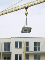 Dźwig budowlany przenoszący materiały budowlane na budowie © tomo81
