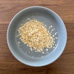 Top view of a cup of dry oats in a blue bowl on a wooden surface