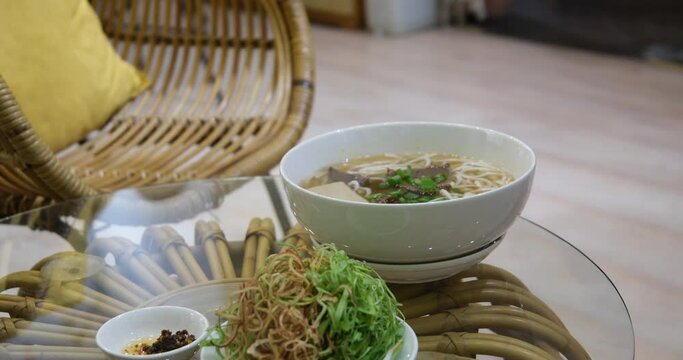 Serving pho bo soup in a restaurant. female tourist travel street market joy and mix and eat Thai rice noodle in bowl and street food alone on holiday. Eating pho soup in Vietnam