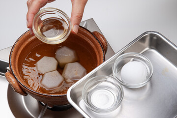 土鍋に下茹でした里芋とだし汁を入れ、さらに砂糖と味醂、日本酒を入れて煮る