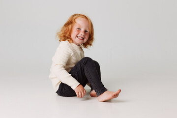 Little girl sitting on floor with legs crossed and hands on knees in a peaceful and relaxing meditation pose