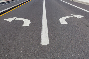 Directional arrows pointing left and right painted on a highway.