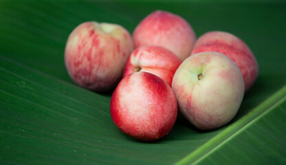 Ripe peaches on a green banana leaf. Selective focus.