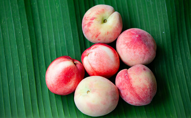 Ripe peaches on a green banana leaf. Selective focus.