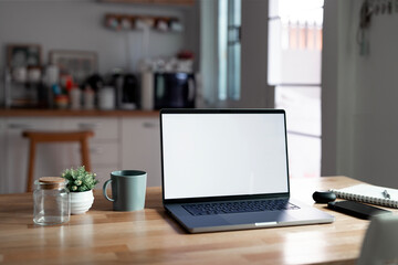 Open laptop with blank screen on a wooden desk in a kitchen room home office