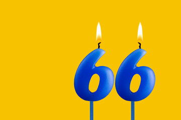 Blue birthday candle on yellow background - Number 66