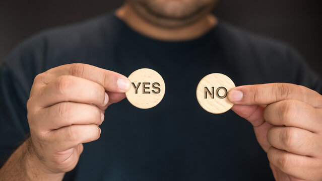 Man hand show yes or no on wood circle block. Yes No choice and decision. Options in difficult situations. True False, decision making.