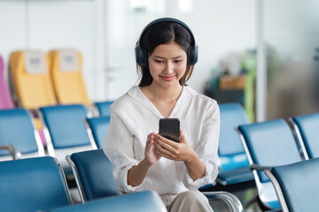 Young Woman Using mobile with Headphones in Airport Lounge, Ready for Travel Adventure, Modern Air Travel Experience, Comfortable Waiting Area, Connected and Relaxed, Pre-Flight Preparation