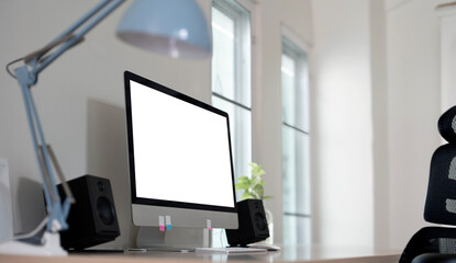 Modern computer desktop with blank screen on table in office interior. Stylish workplace